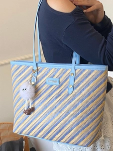 Blue and yellow woven striped tote bag with light blue leather straps and plush charm