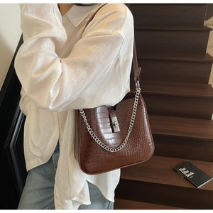 Detail of brown crocodile pattern leather shoulder bag with silver chain and metal lock