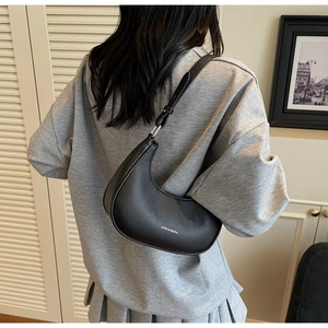 Détail du sac demi-lune en cuir grainé noir avec une bandoulière réglable et élégante
