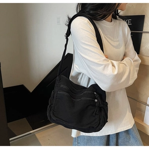 Detail view of black canvas crossbody bag featuring three-layer parallel zipper design
