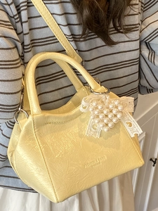 Borsa a secchiello giallo crema minimalista con ciondolo di perle e tracolla