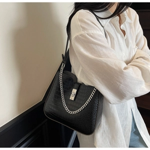 Detail view of black faux crocodile texture shoulder bag with silver metal lock and chain