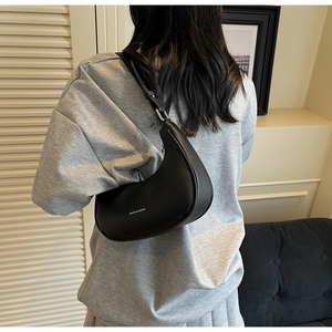 Détail d'un sac hobo en cuir grainé noir avec boucle argentée et lettrage de la marque