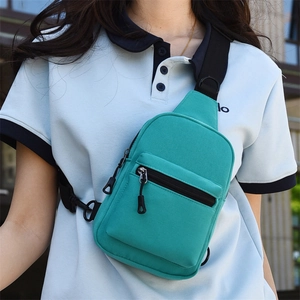 Detail of teal canvas chest bag featuring sturdy zipper pockets and black nylon strap