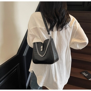 Detailed view of black crocodile pattern bucket bag with silver buckle and metal chain