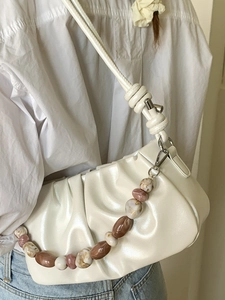 Sac à aisselle plissé blanc crème avec chaîne ambrée porté sur chemise blanche