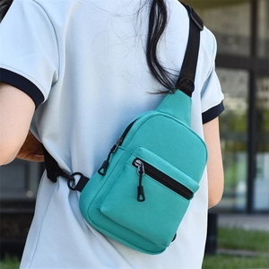 Detail view of teal canvas crossbody bag worn by model showing black nylon strap