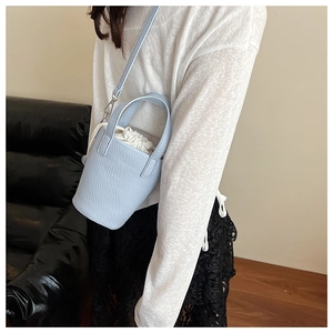 Detail of light blue bucket bag with pebble leather texture and drawstring liner