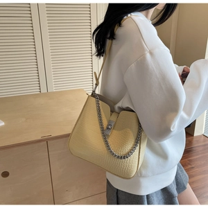 Detail of light yellow crocodile pattern shoulder bag with silver chain and metal buckle