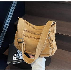 Detail view of khaki canvas crossbody bag with multiple zippers and wide strap