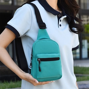 Detail showing teal canvas chest bag with dual zipper pockets and adjustable black strap