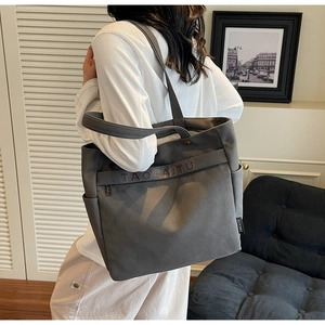 Detailed view of grey canvas tote bag with TAOCAITU logo, side pocket and zipper closure