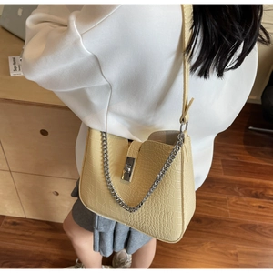Close-up of yellow crocodile texture shoulder bag with silver lock and metal chain