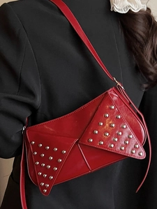 Red asymmetric rivet shoulder bag in shiny leather with retro punk aesthetic