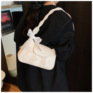 Detail of off-white underarm bag featuring a twisted strap and elegant lace bow accent