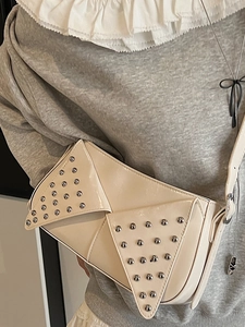 Cream patent leather rivet shoulder bag with triangle flap shown on a model