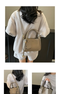 Détails du sac seau gris texture litchi avec pendentif chien et boucles dorées élégantes