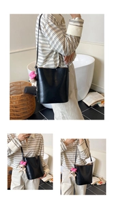 Detailansicht einer schwarzen Leder-Beuteltasche mit verstellbarem Riemen und Plüsch-Anhänger