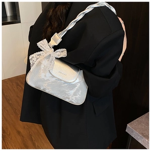 Detail of silver metallic shoulder bag with lace bow on model in black blazer
