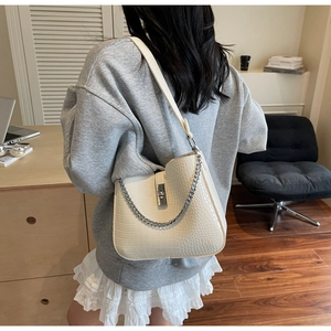 Detail of off-white crocodile embossed leather shoulder bag with silver buckle and chain