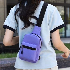 Detailed back view of a purple nylon crossbody bag worn by a model in outdoor setting