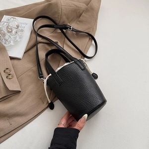 Macro shot of black litchi grain leather bucket bag with drawstring liner and top handle