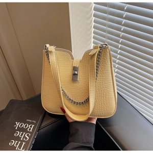Close-up of yellow crocodile texture crossbody bag with silver chain and twist lock