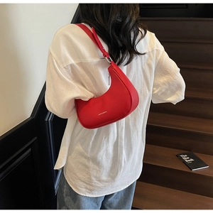 Détail d'un sac à bandoulière demi-lune rouge en cuir de qualité à motif litchi