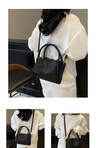 Détail du sac seau noir en cuir grainé avec un charmant pendentif chien et ferrures dorées
