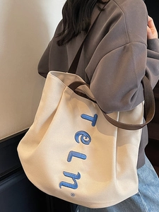 Large beige canvas tote bag with brown straps and blue embroidery for daily commute