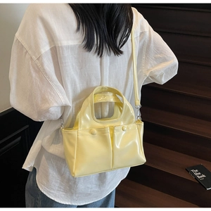 Detail of stylish bright yellow glossy shoulder bag featuring double front buckle pockets