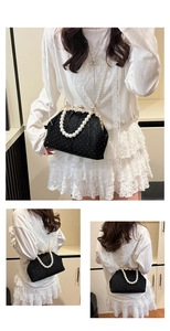 Detailed view of black velvet handbag with white polka dots and pearl strap handle