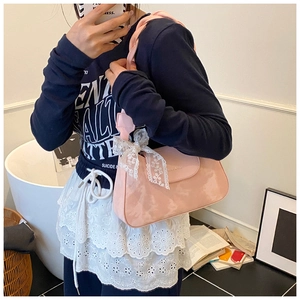 Detail showing pink underarm bag with white lace bow and textured woven shoulder strap