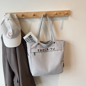 Light gray canvas tote bag hanging on a wooden rack with a chic urban casual style