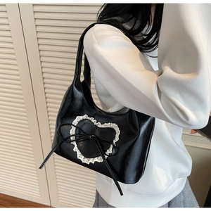 Vista laterale della borsa tote nera con cuore in pizzo bianco indossata dal modello