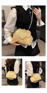 Close-up of pleated evening bag with pearl handles and sparkling gold glitter texture