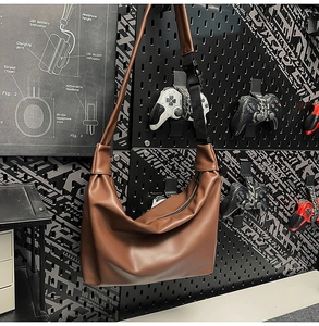 Detail of brown PU leather tote bag featuring adjustable strap and tactical buckle closure