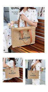 Detail of woven straw tote bag featuring Summer text embroidery and brown leather handles
