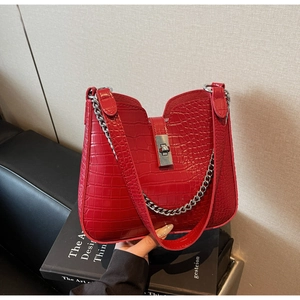 Detail of red crocodile texture leather bag featuring silver twist lock and chain