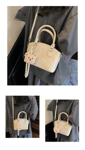 Detail of a cream bucket bag with faux lizard texture and a cute plush bear pendant