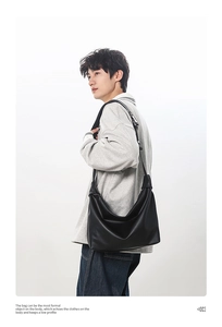 Detail view of black leather tote bag with adjustable strap worn by a model