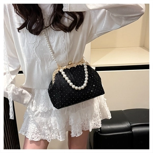 Detail of black velvet evening bag with sparkling rhinestones and pearl chain strap