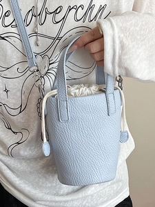 Mini light blue bucket bag in lychee leather with white drawstring pouch and strap