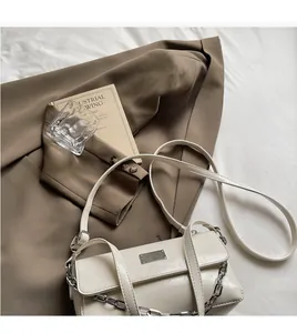 Detailed shot of cream white baguette bag with silver chain strap and metal logo plate