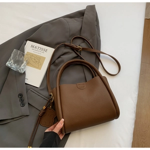 Détail d'un sac cabas marron à texture litchi avec gaufrage mode sur fond de costume gris
