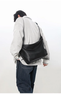 Rear view of a large black minimalist tote bag worn as a crossbody bag for daily use