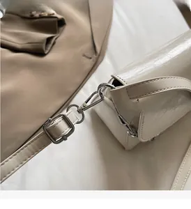 Close-up of cream baguette bag with glossy texture and silver chain metal hardware