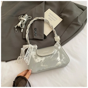 Detail view of silver underarm bag with cloud texture, lace bow, and shoulder strap