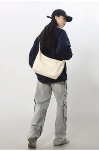Detailed view of cream-white large capacity half-moon crossbody tote bag on a model