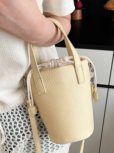 Mini beige bucket bag in lychee pattern leather with a cream canvas drawstring pouch